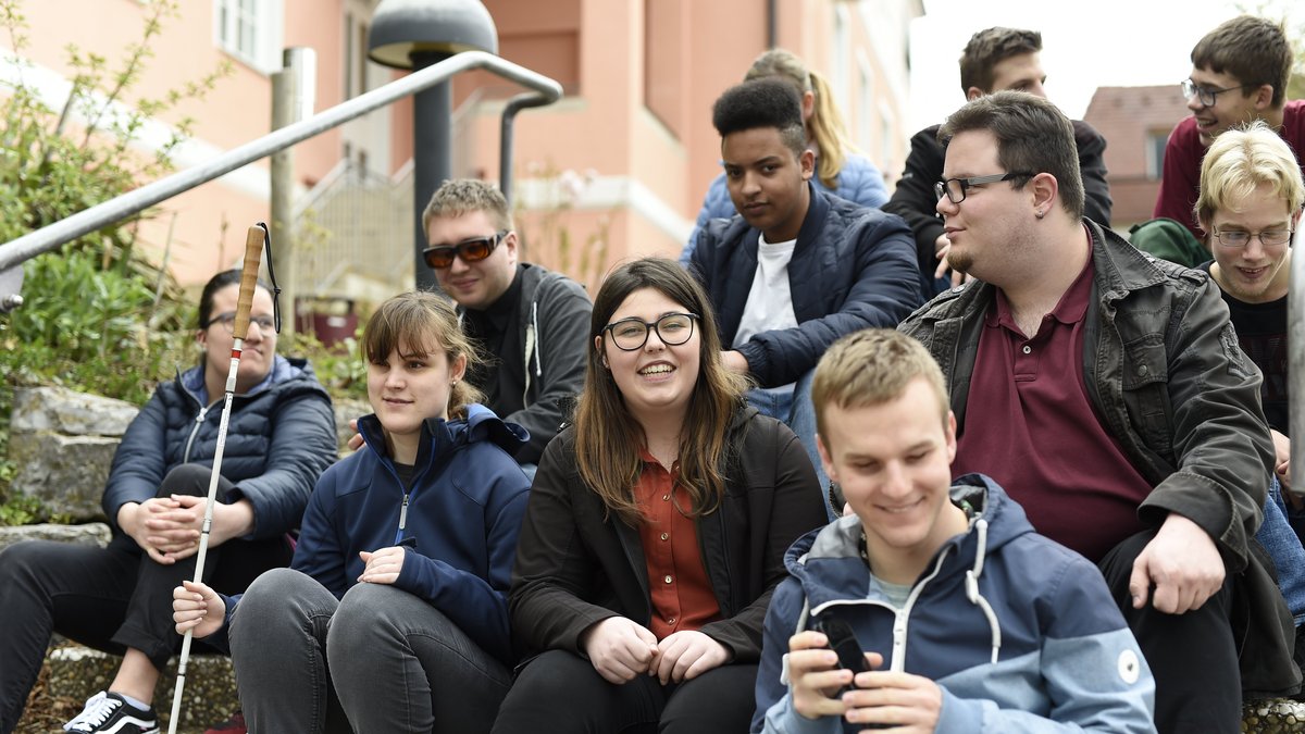 Gruppe Jugendlicher sitzt auf einer Treppe vor dem Kräherwaldgebäude