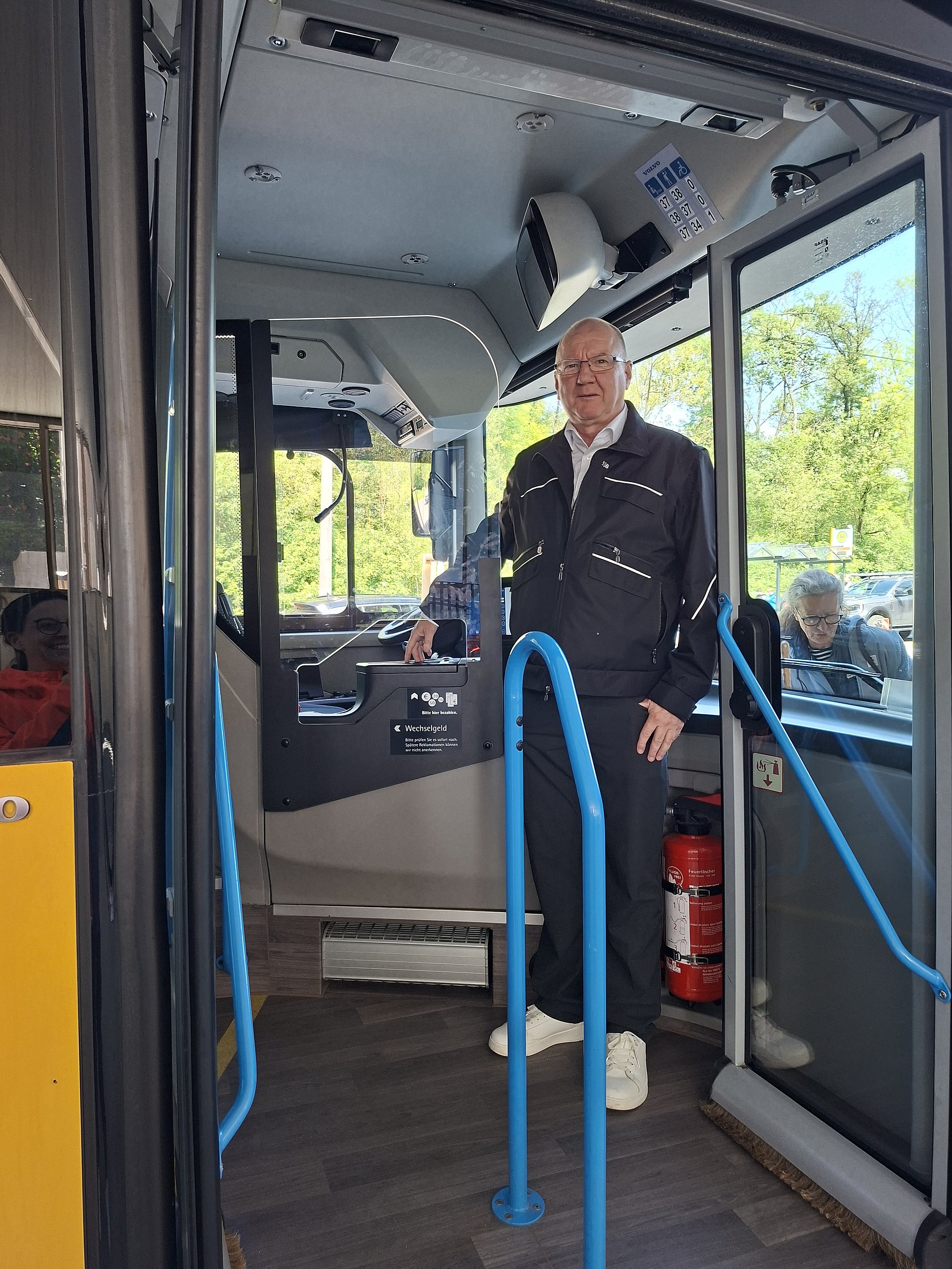 In einem Bus steht ein freundlicher Busfahrer in der geöffneten Bustür